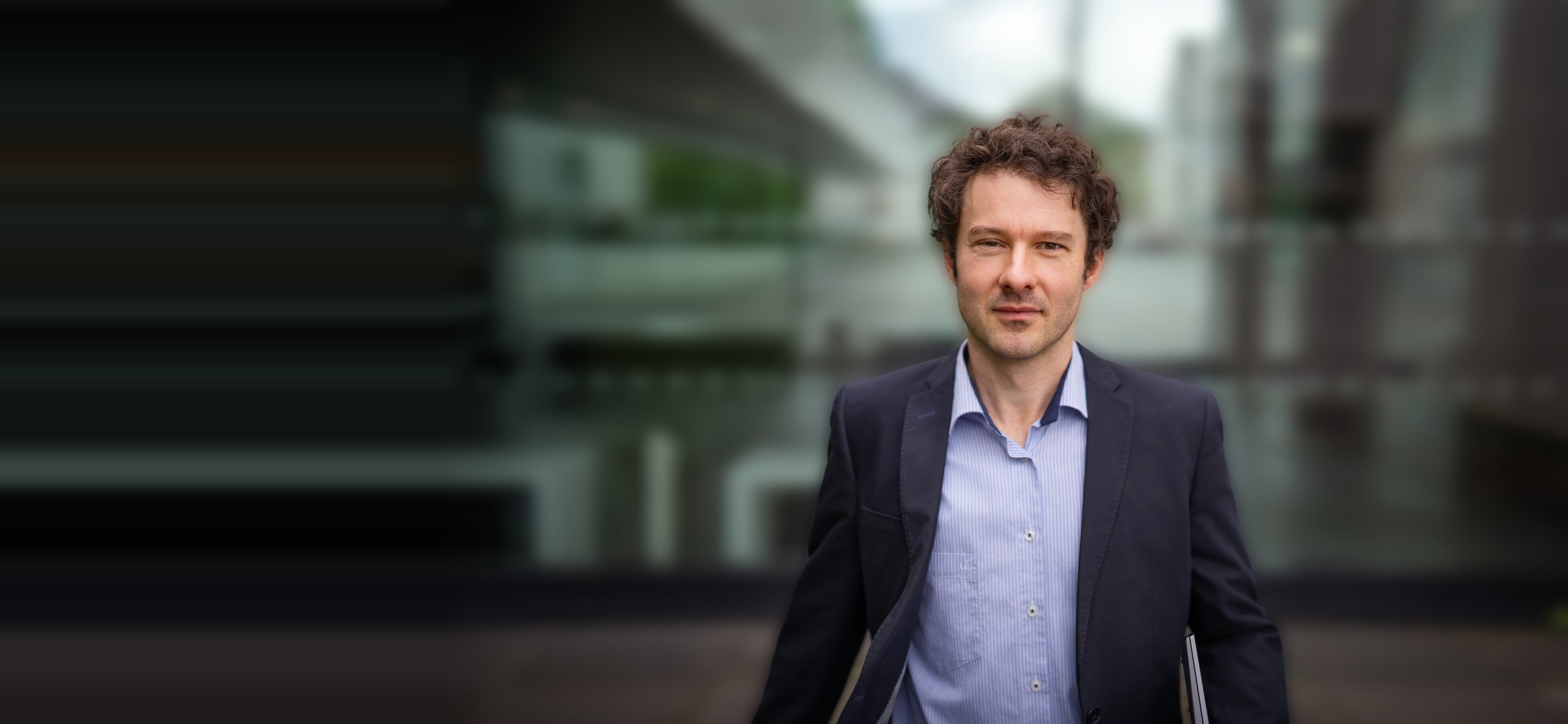Ilja in front of a modern glass office building